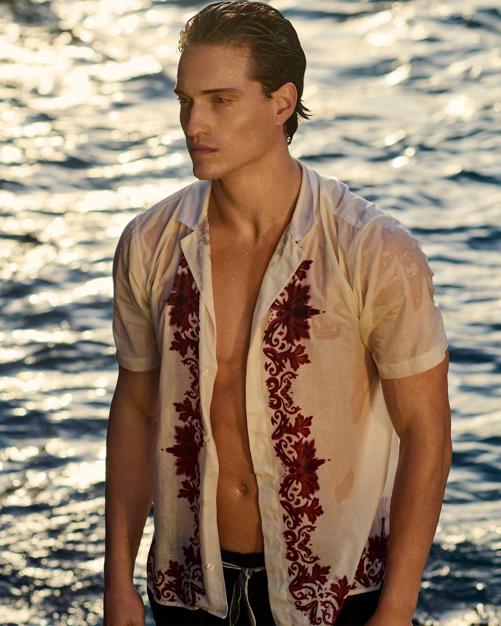 Man wearing a white shirt with red patterns by water