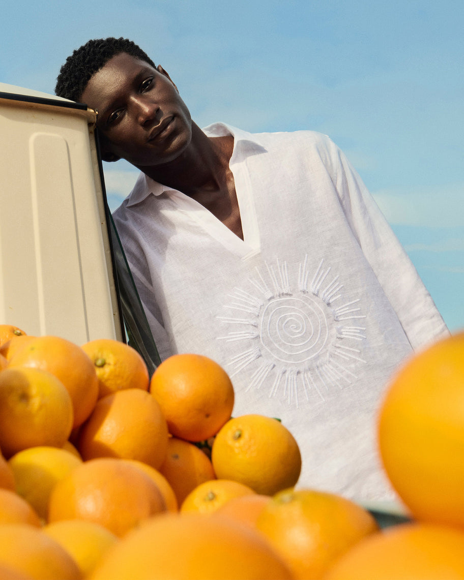 Person leaning against a car with oranges in the foreground