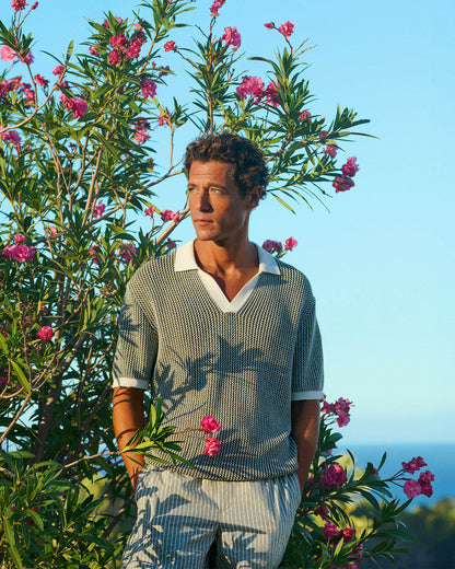 Man standing among pink flowering bushes with a clear blue sky in the background