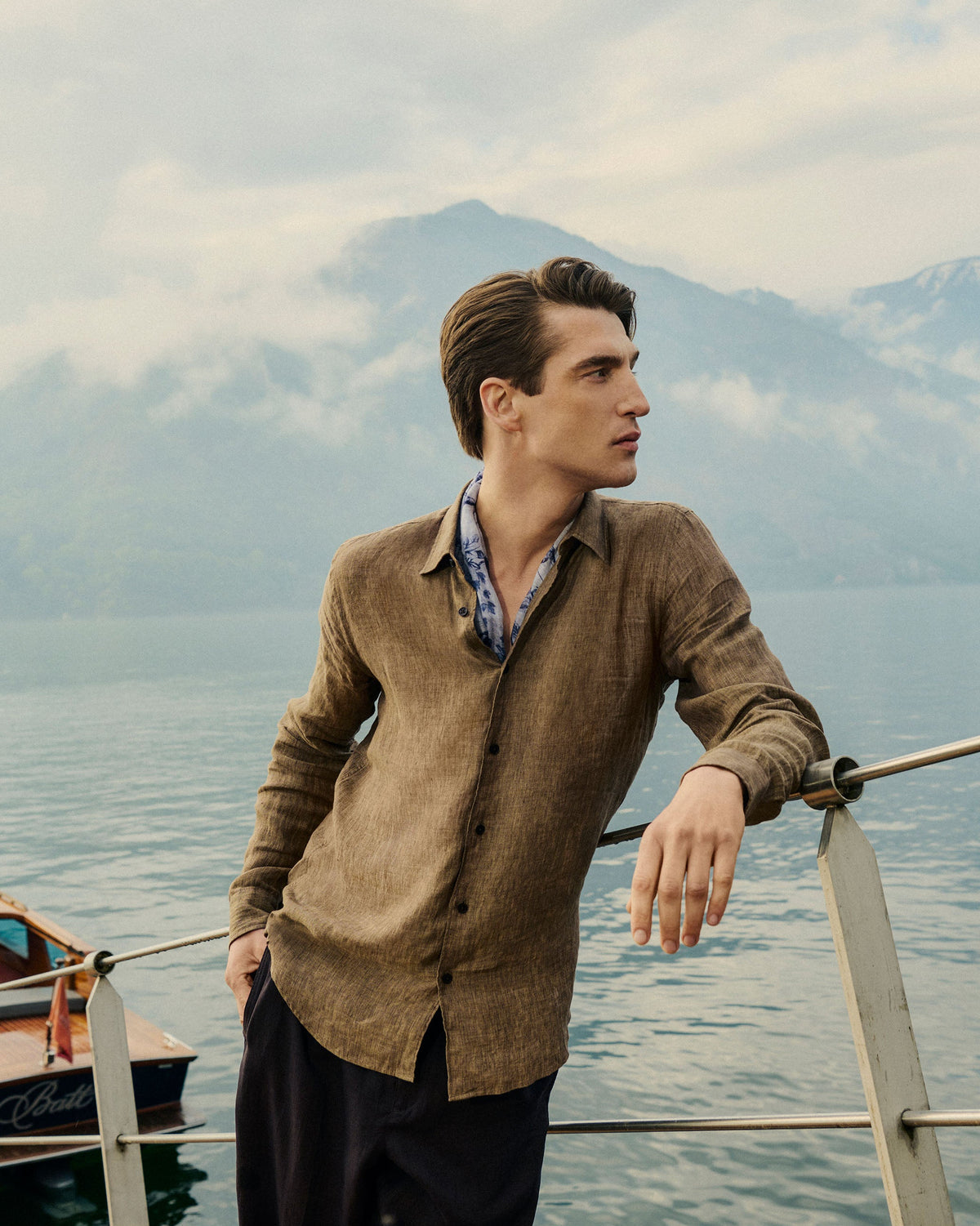 Man standing on a boat with mountains and water in the background