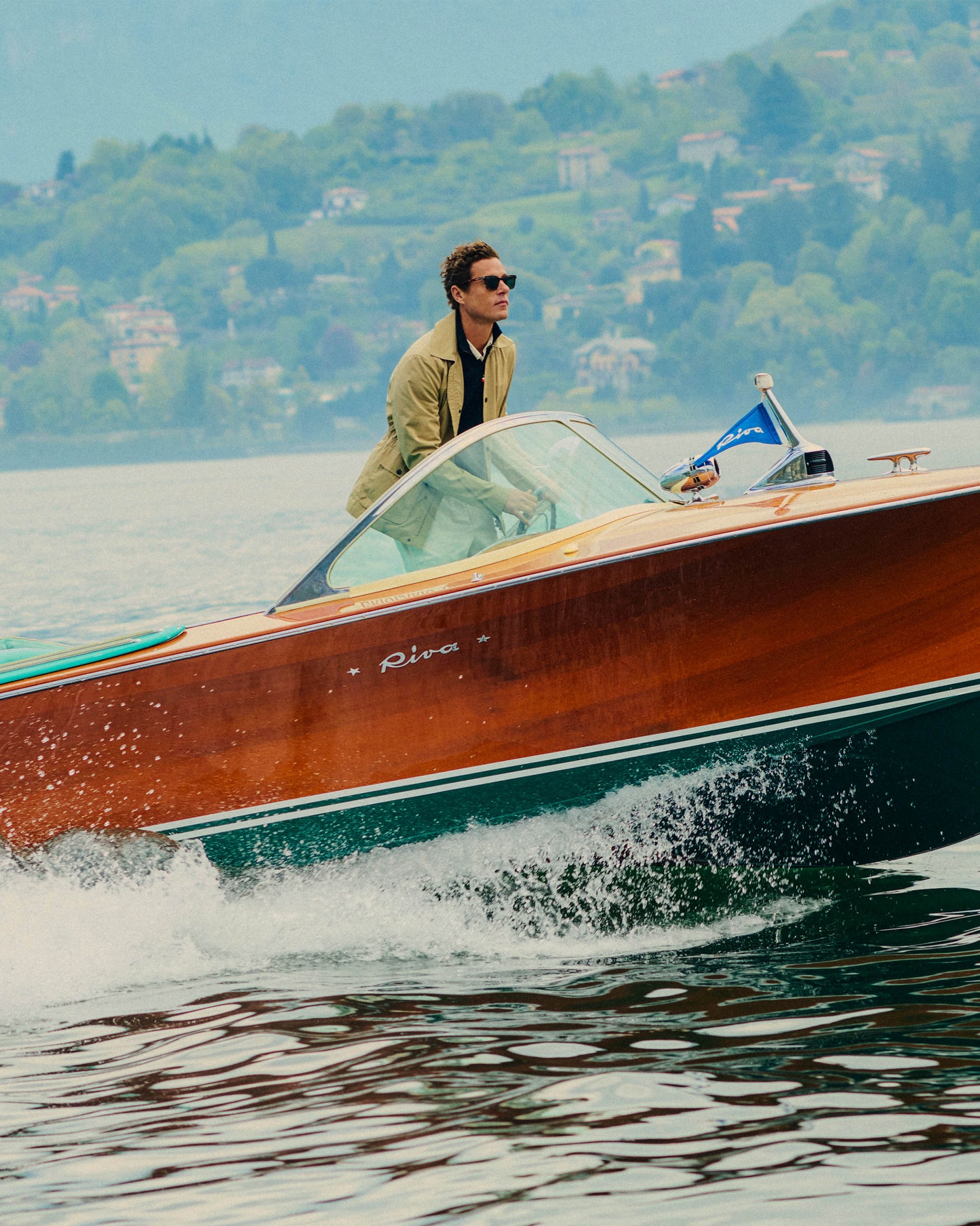 Man driving a wooden boat on a lake with a scenic background