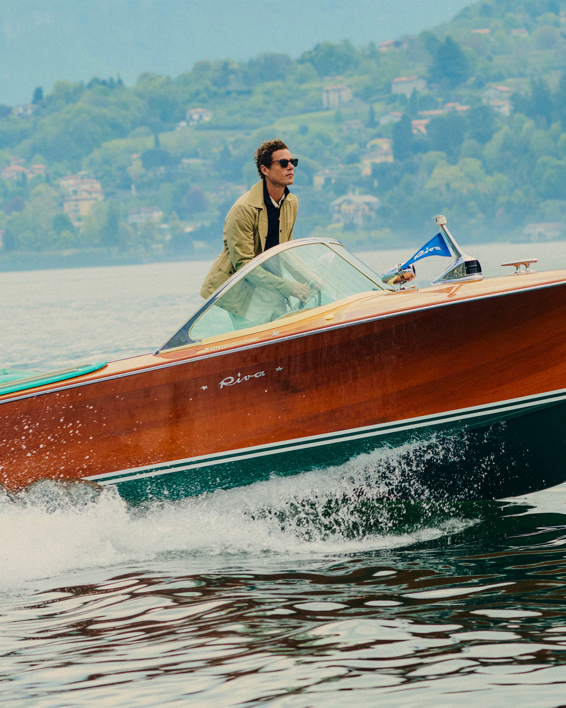 Man driving a wooden boat on a lake with a scenic background