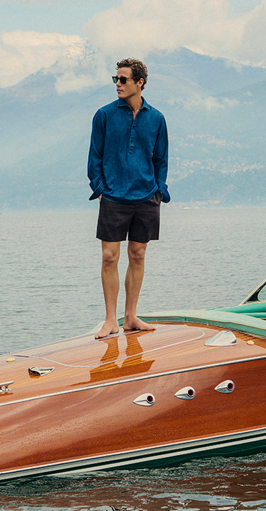 Man standing on a boat with mountains in the background