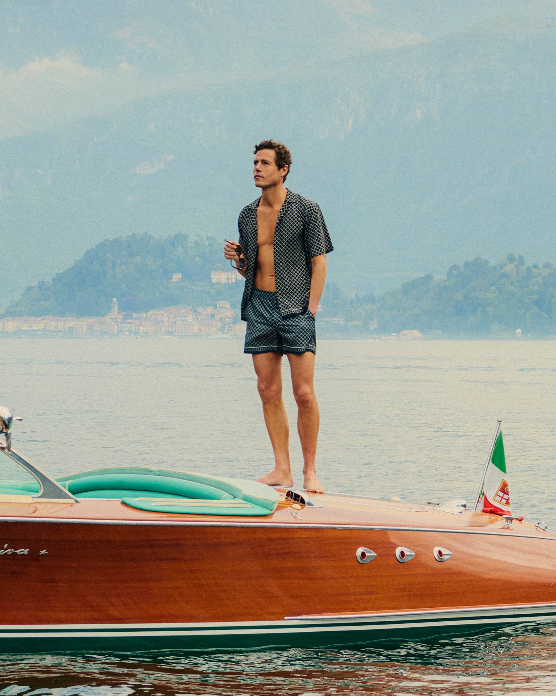 Man standing on a boat with mountains in the background
