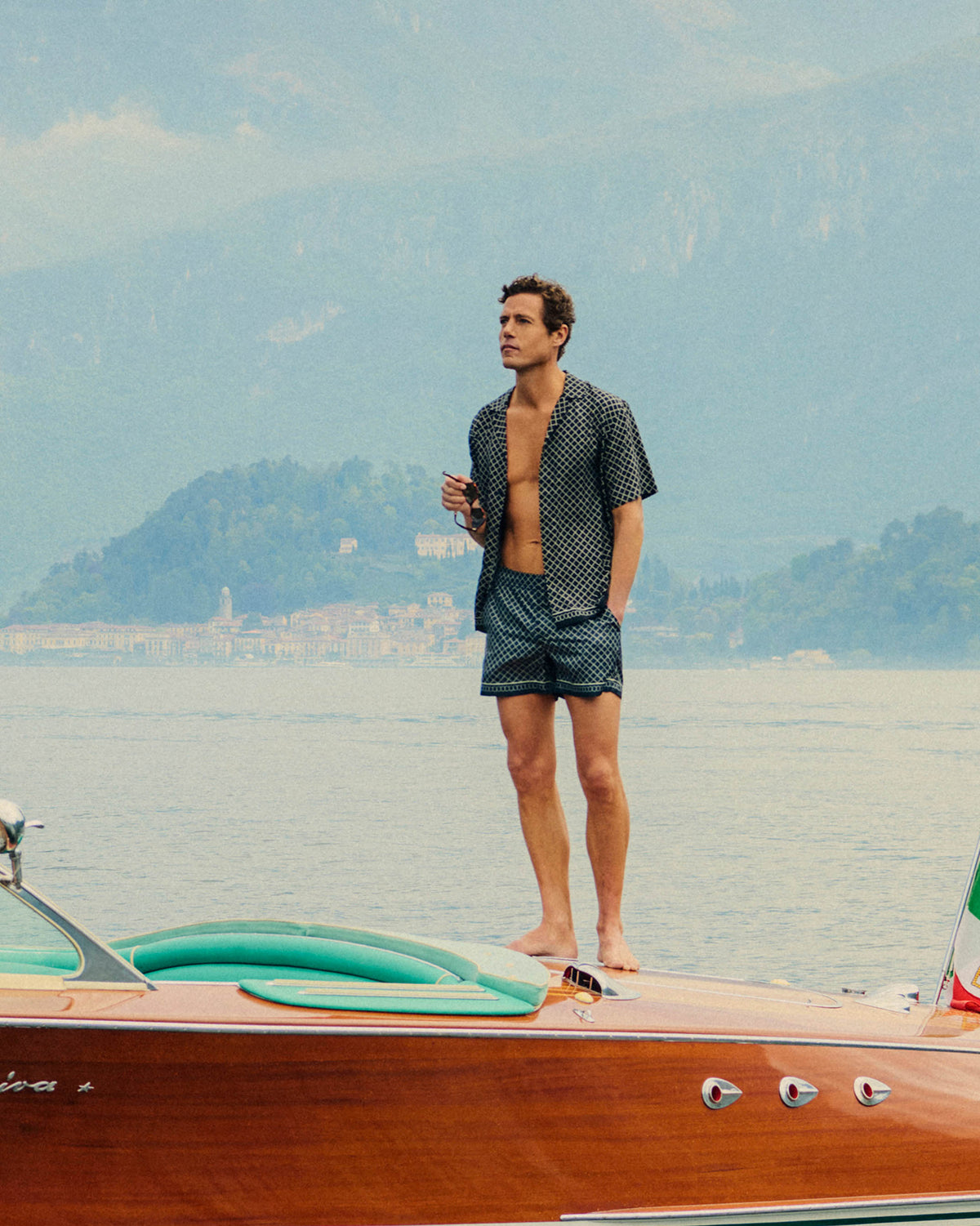 Man standing on a boat with mountains in the background