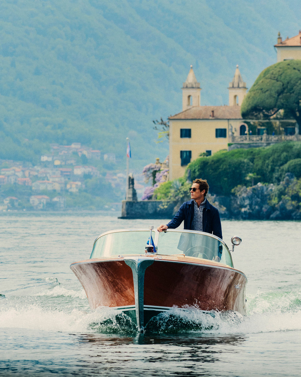 Man driving a boat on a lake with a scenic background