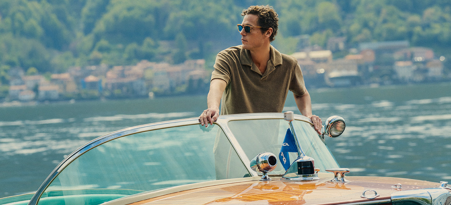 Man on a boat in a scenic location with water and trees in the background
