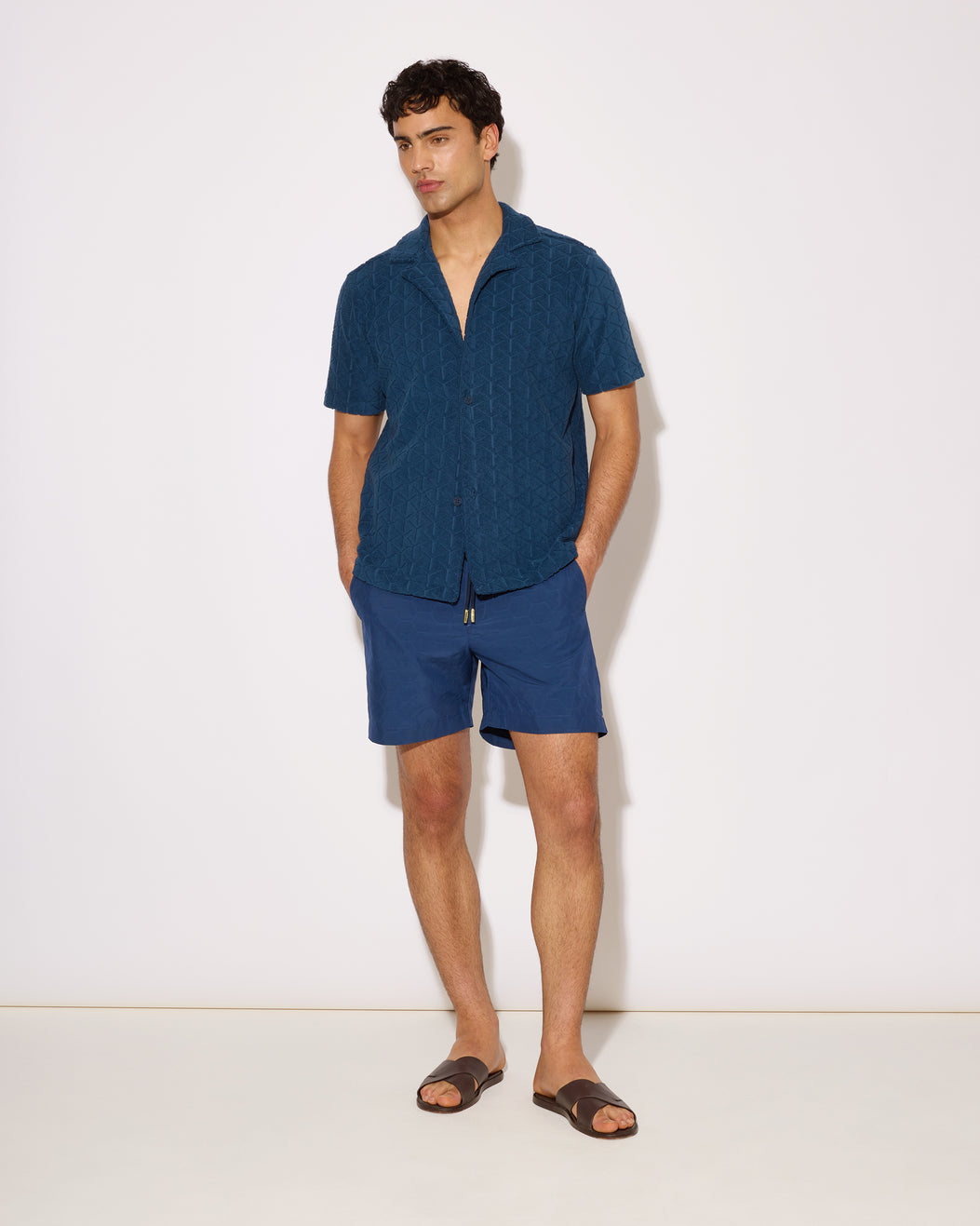 Man wearing a blue textured shirt and shorts on a white background