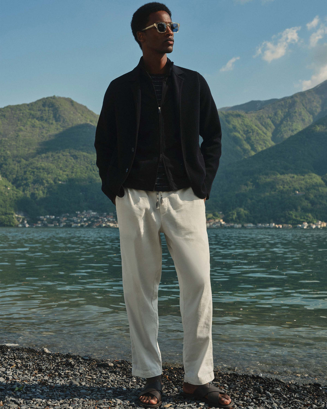 Man standing by a lake with mountains in the background