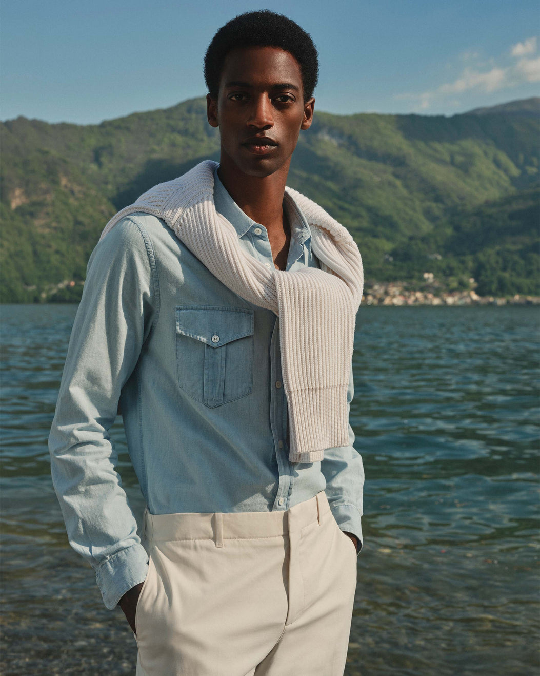 Man standing by a lake with mountains in the background
