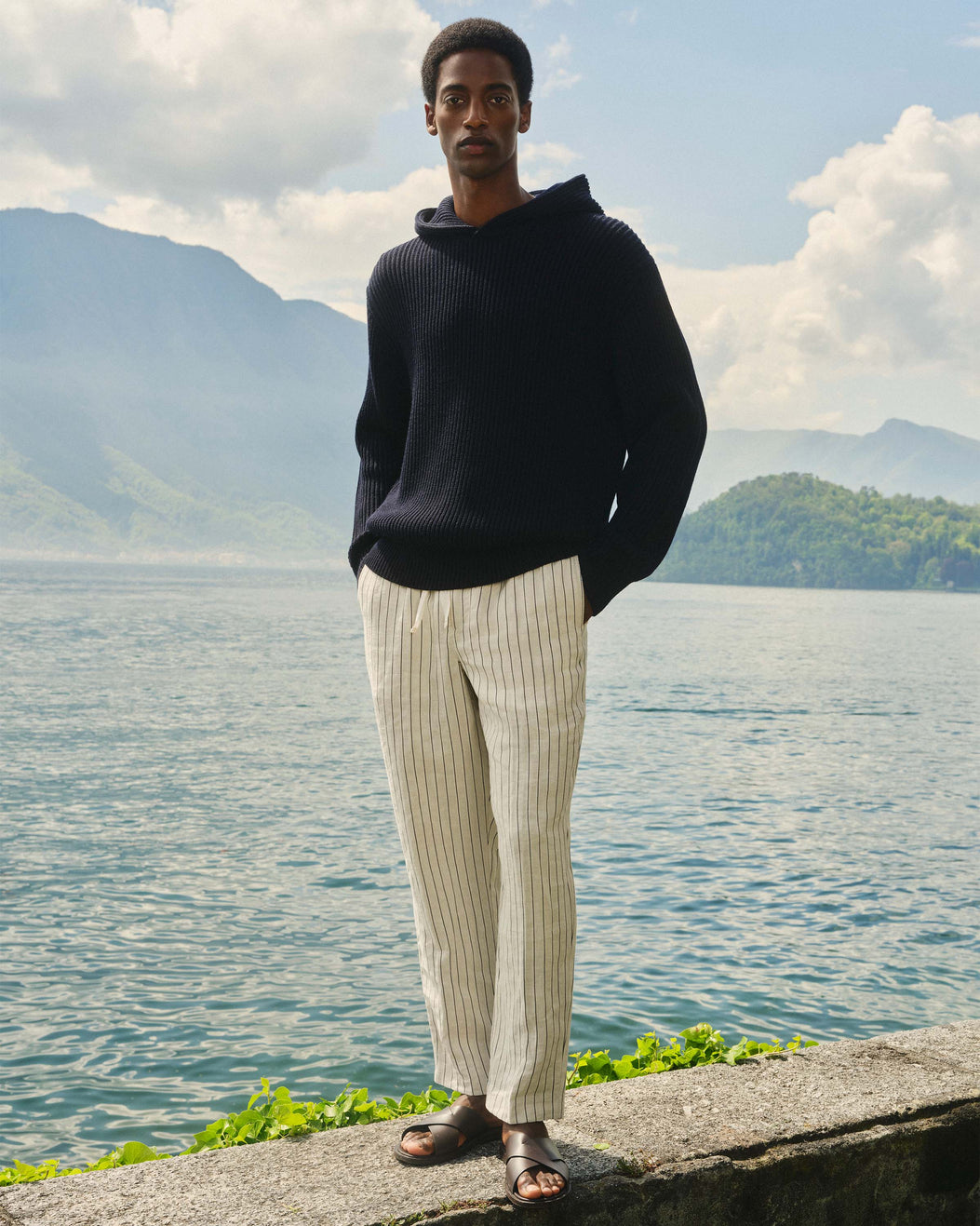 Man standing by a lake with mountains in the background