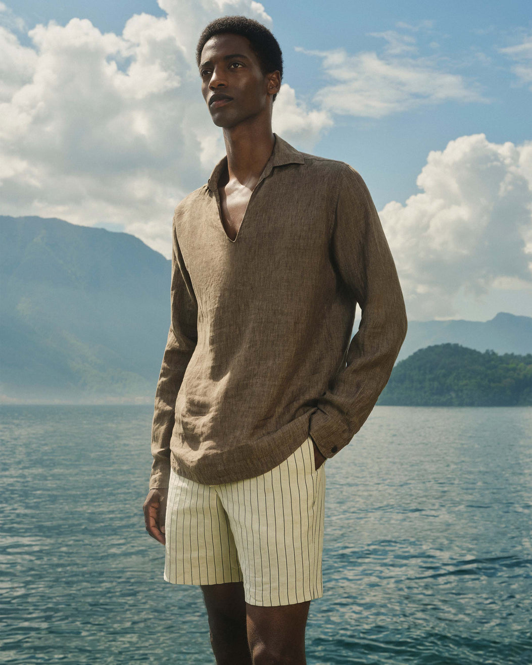 Man standing by a lake with mountains in the background