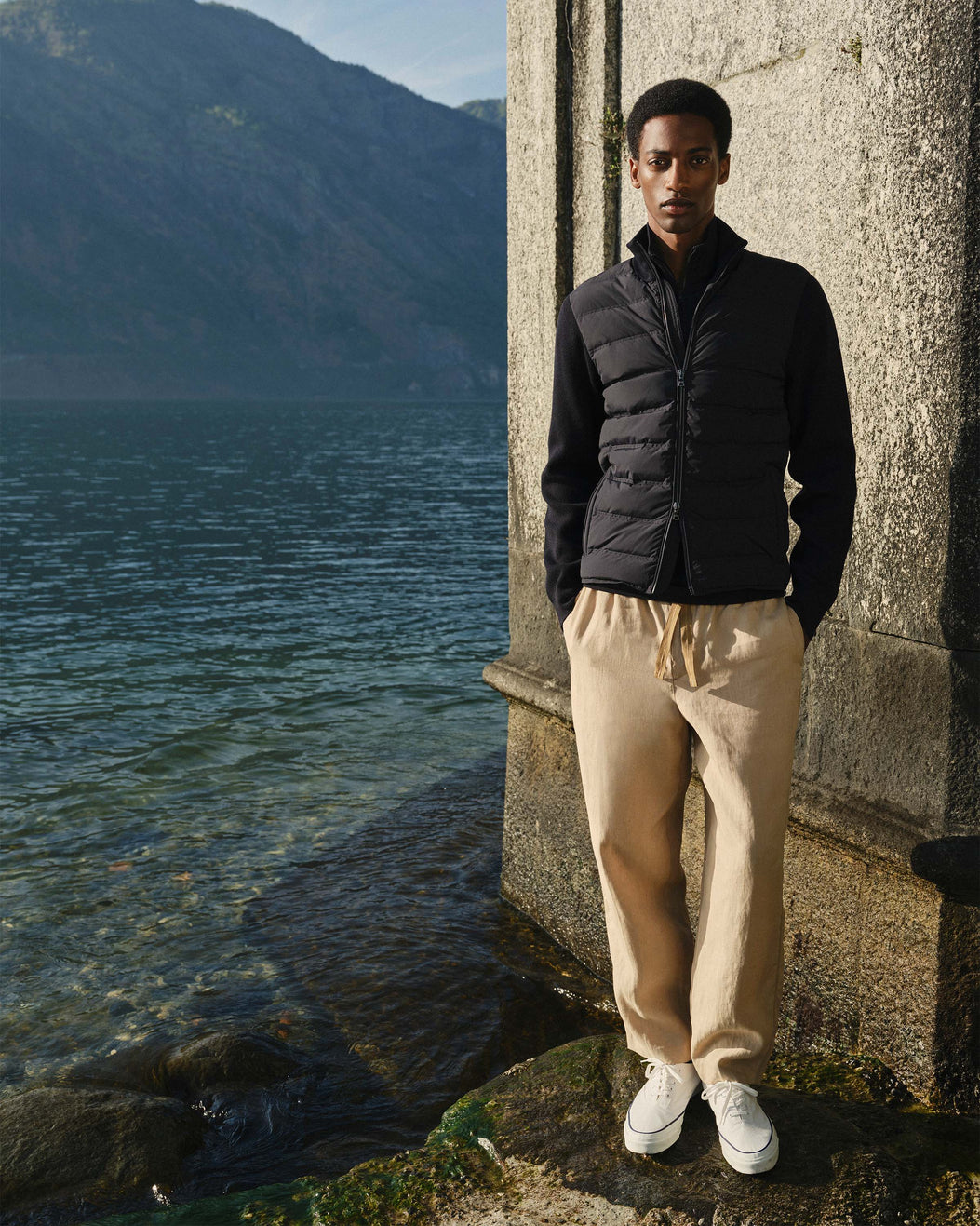 Man standing by a body of water with mountains in the background