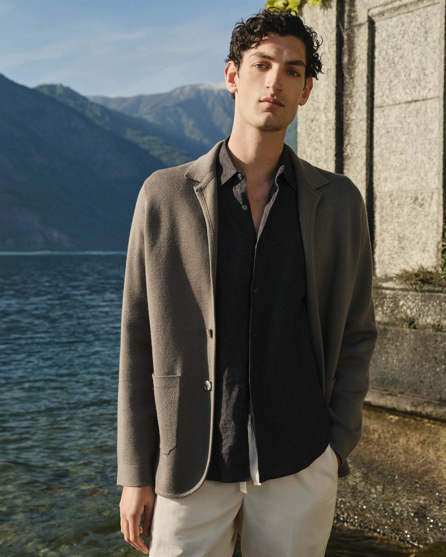 Man standing by a lake with mountains in the background