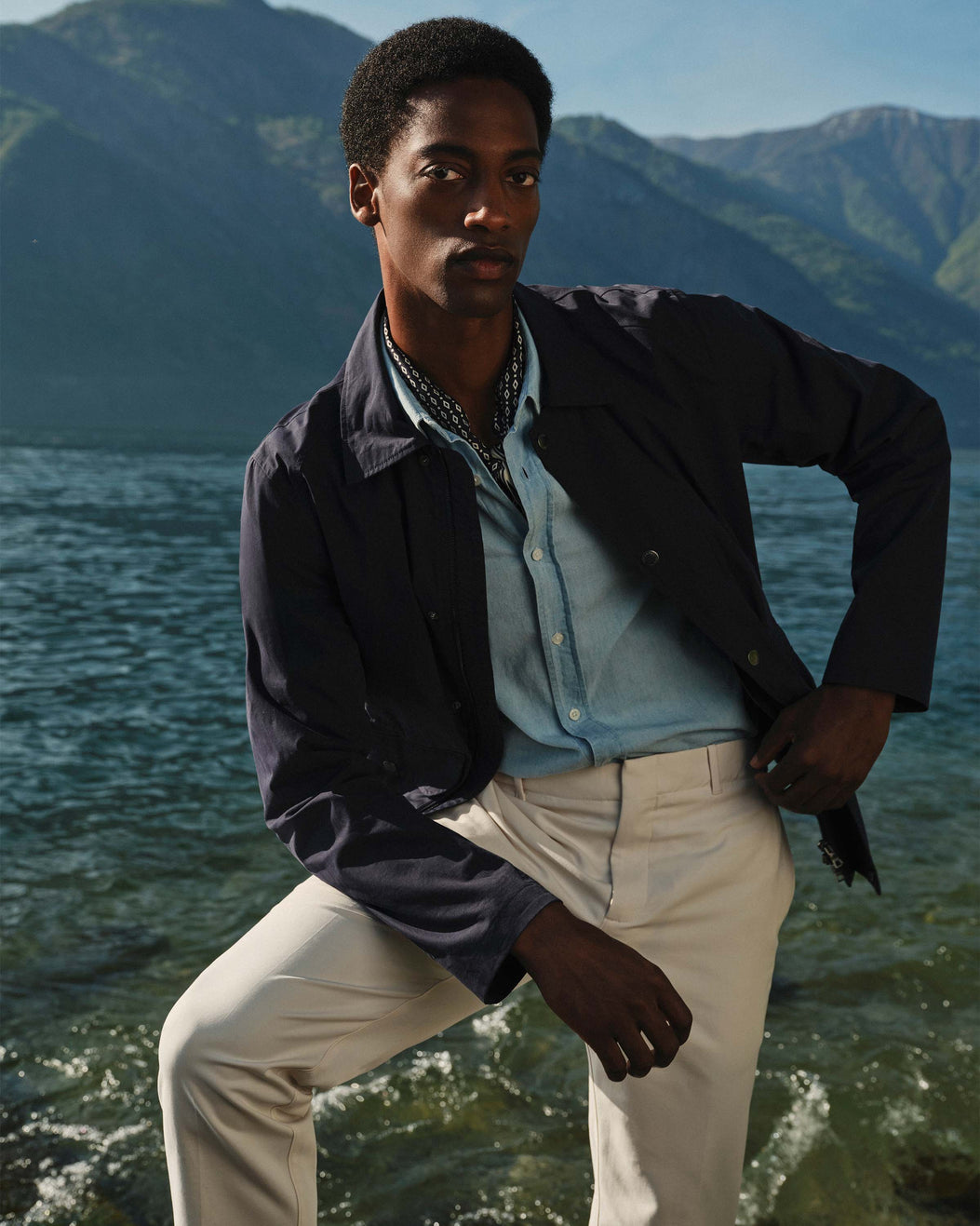 Man standing by a lake with mountains in the background