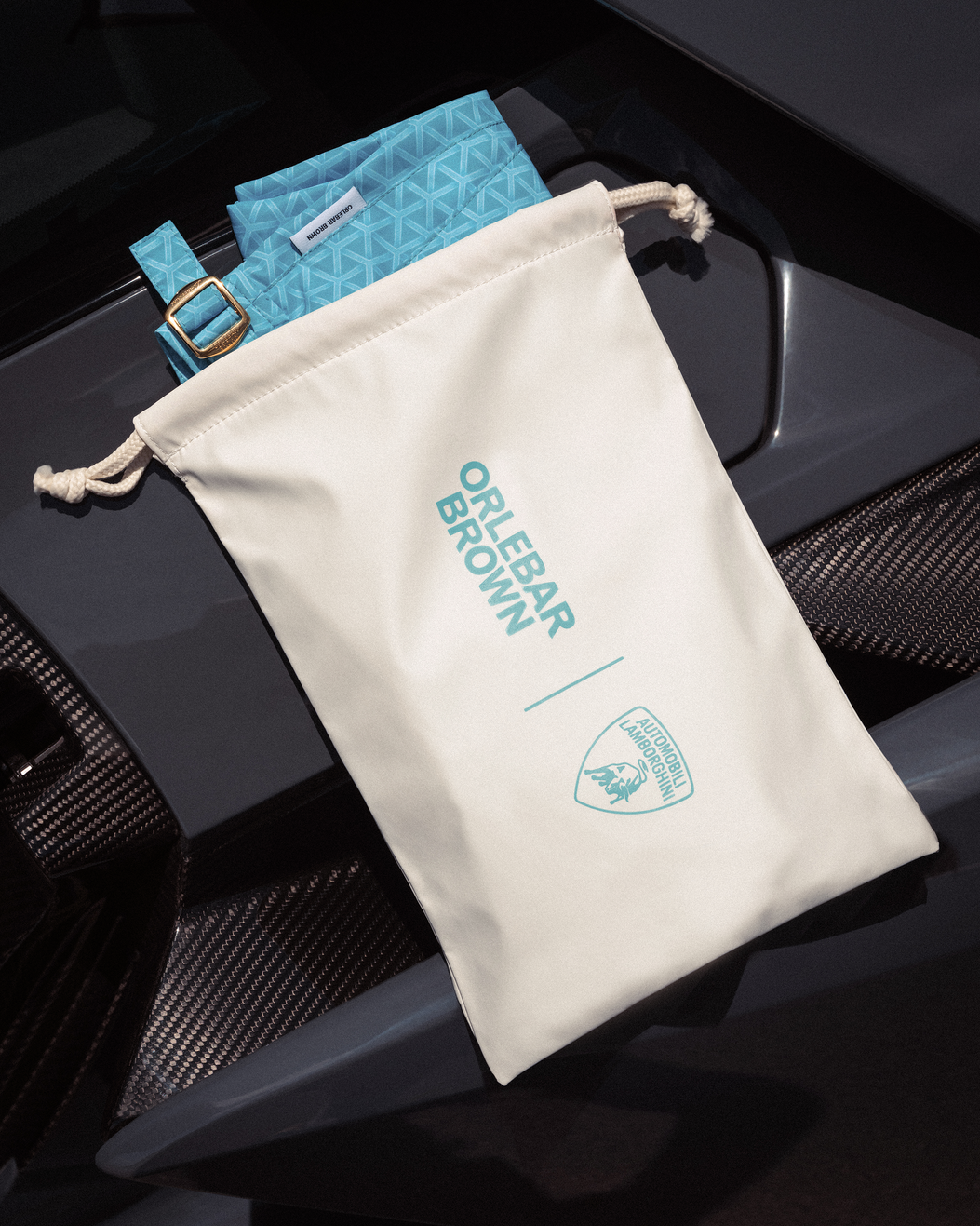 White drawstring bag with 'Orlebar Brown' branding on a black textured surface.