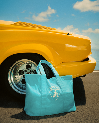 Blue tote bag with a logo on a yellow car by the sea