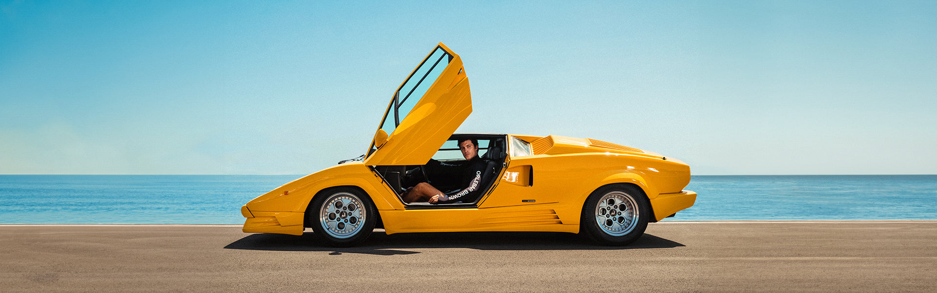 Yellow sports car with open door on a beach