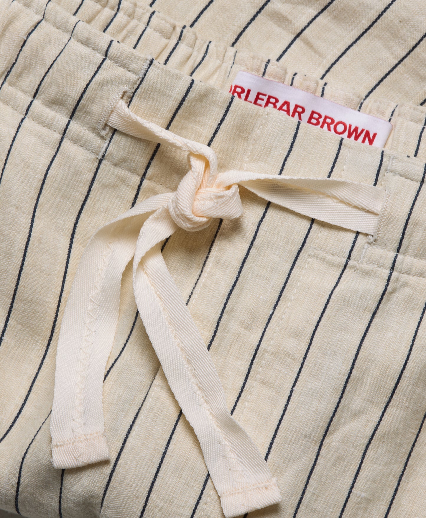 Close-up of a pinstripe garment with a brand label on a beige background