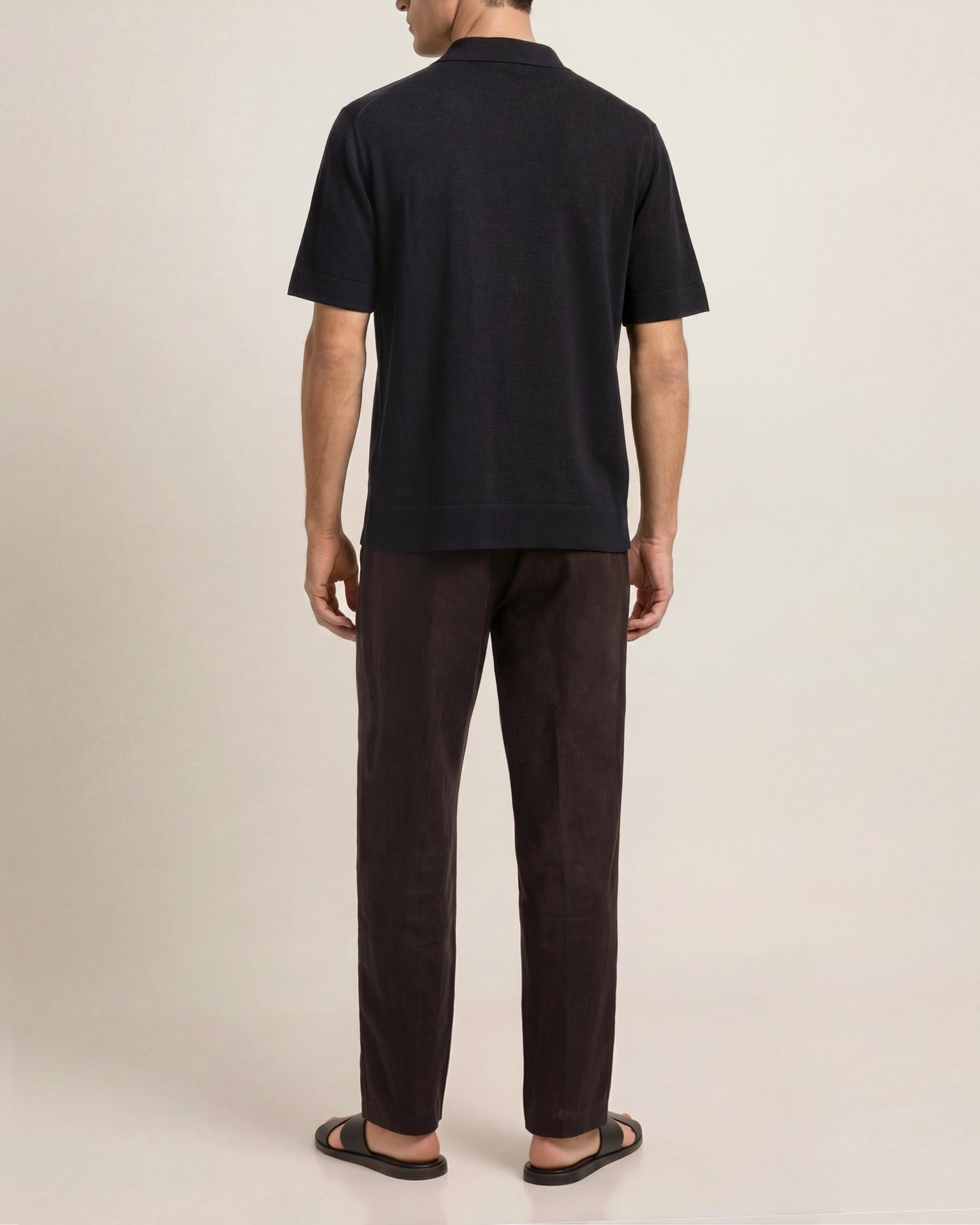 Person wearing a black t-shirt and dark pants on a plain background