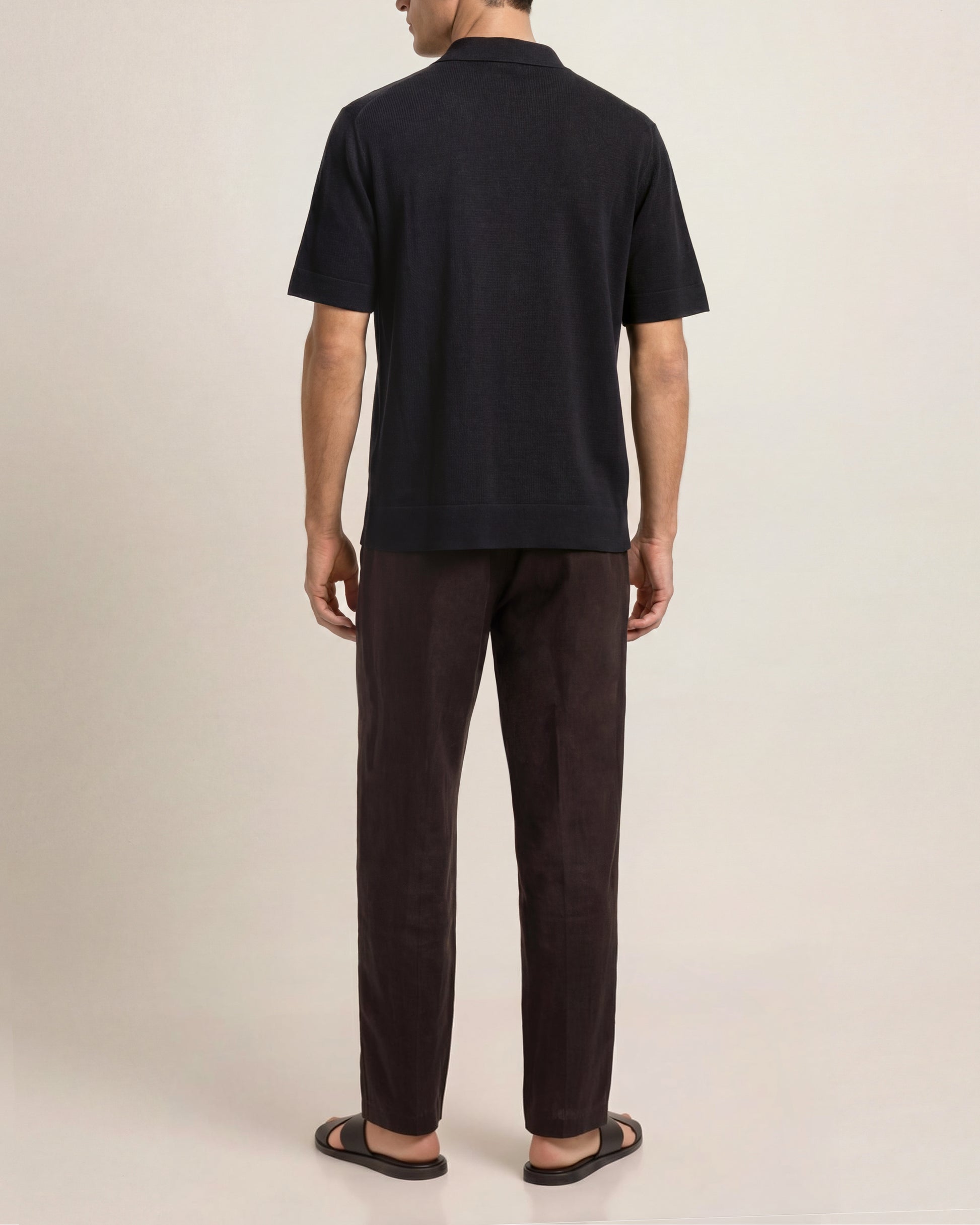 Person wearing a black t-shirt and dark pants on a plain background