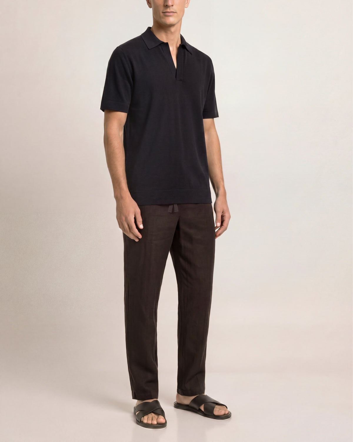 Man wearing a black polo shirt and dark pants on a white background