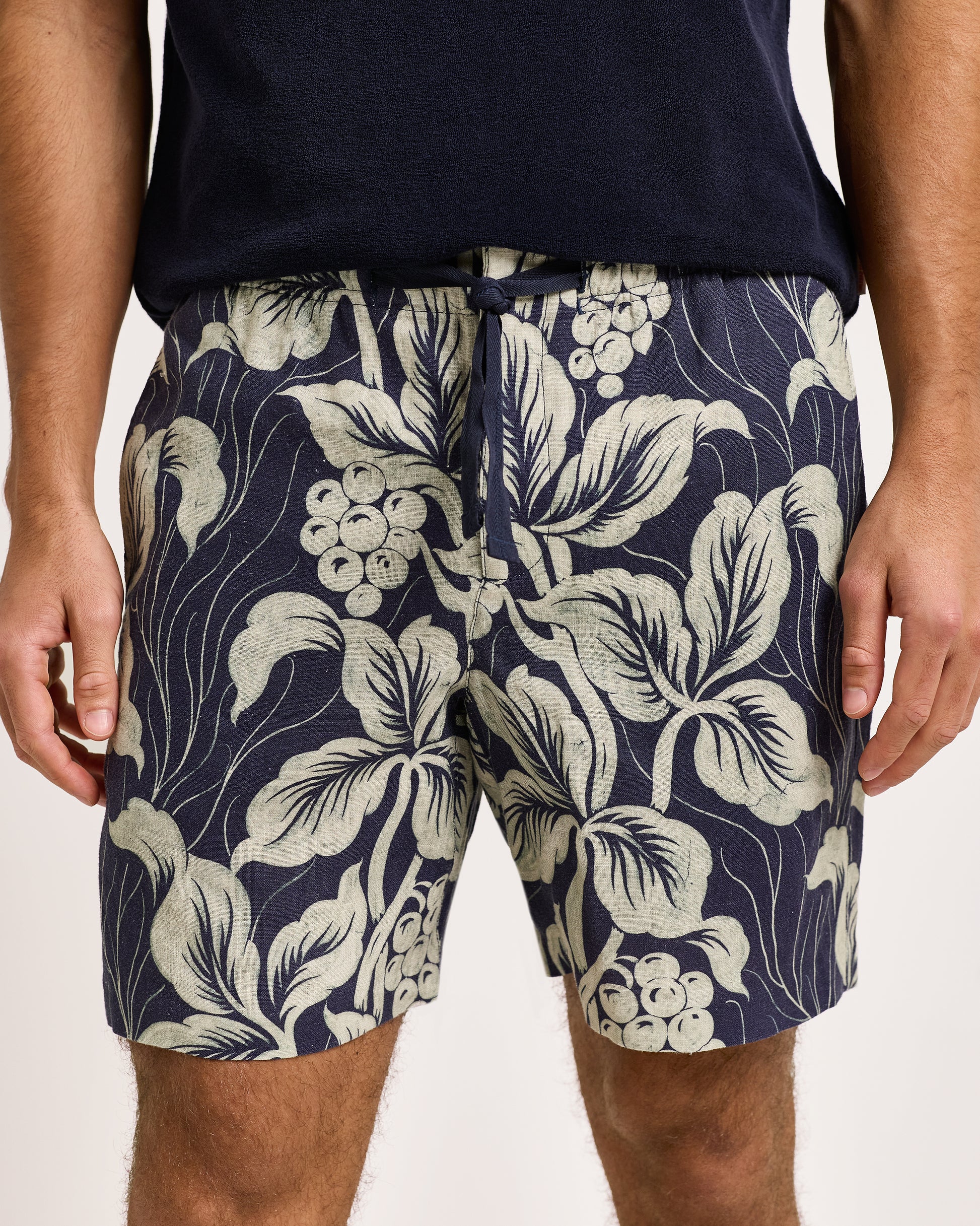 Navy shorts with a white floral pattern worn by a person on a light background