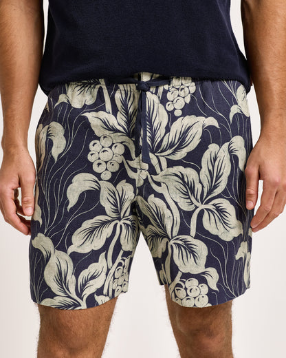 Navy shorts with a white floral pattern worn by a person on a light background
