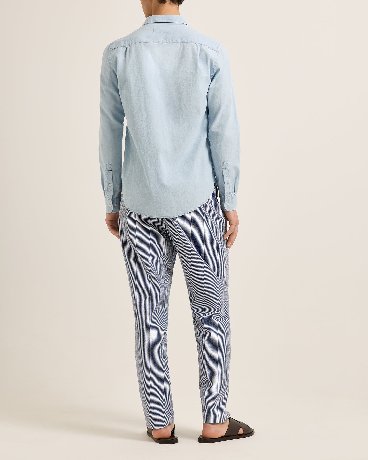 Person wearing a light blue shirt and pants on a plain background