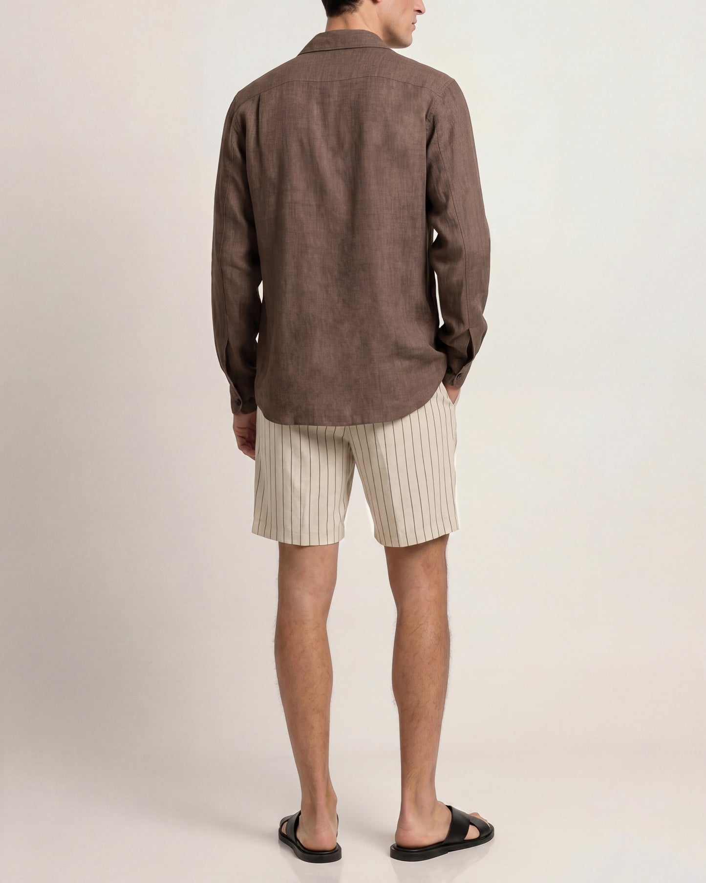 Person wearing a brown shirt and beige shorts on a plain background