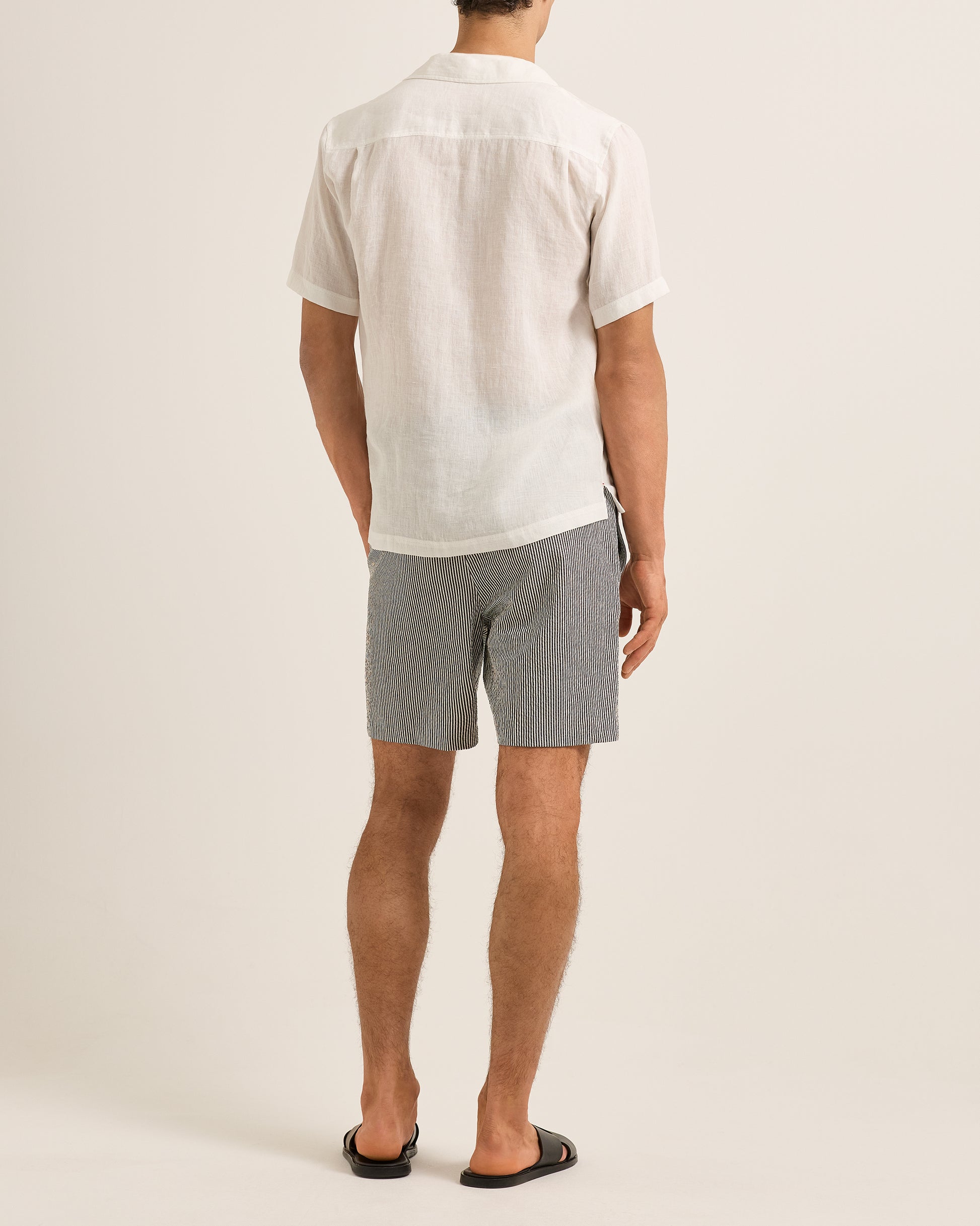 Person wearing a white shirt and gray shorts on a plain background