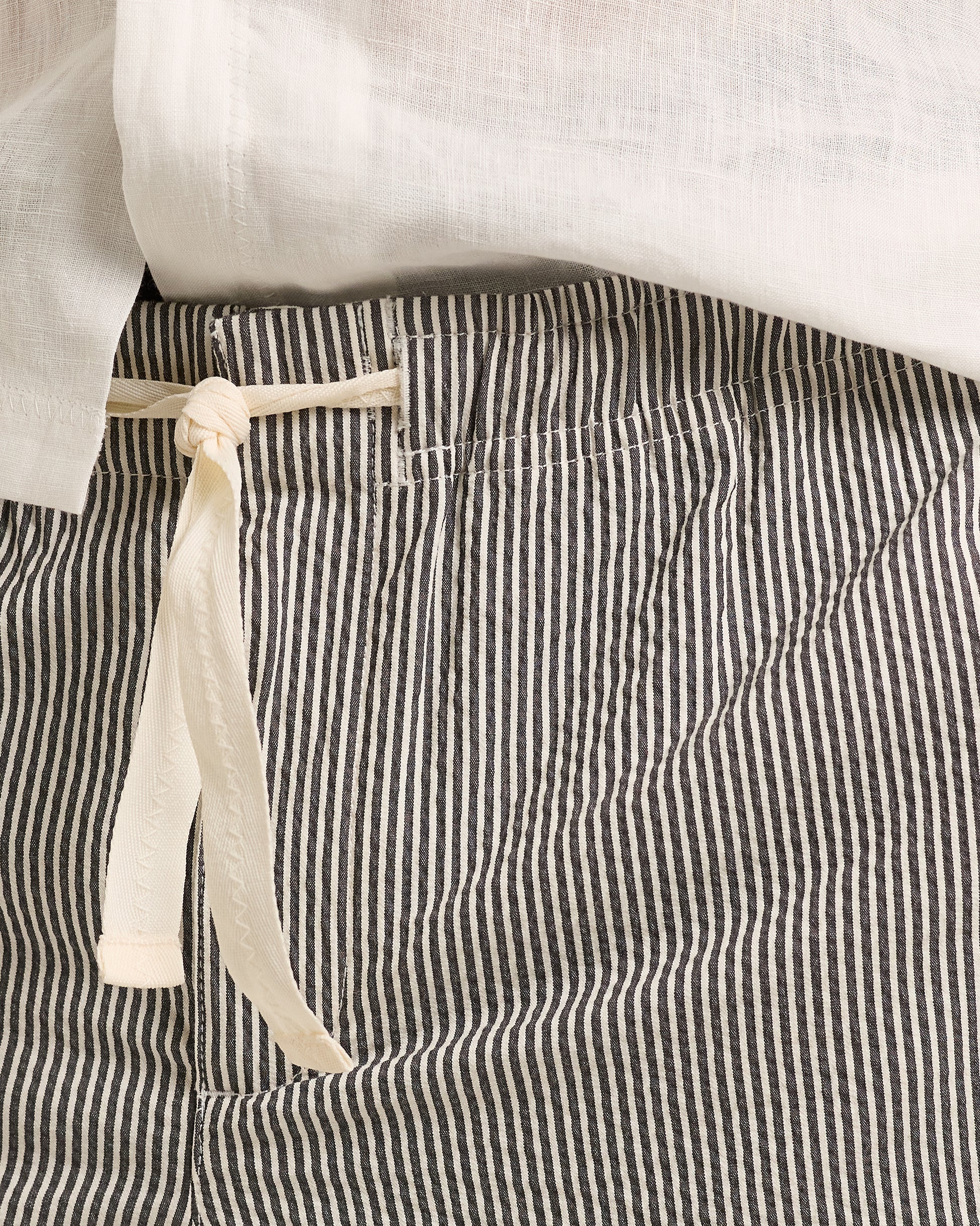 Striped pants with a white ribbon tie on a neutral background