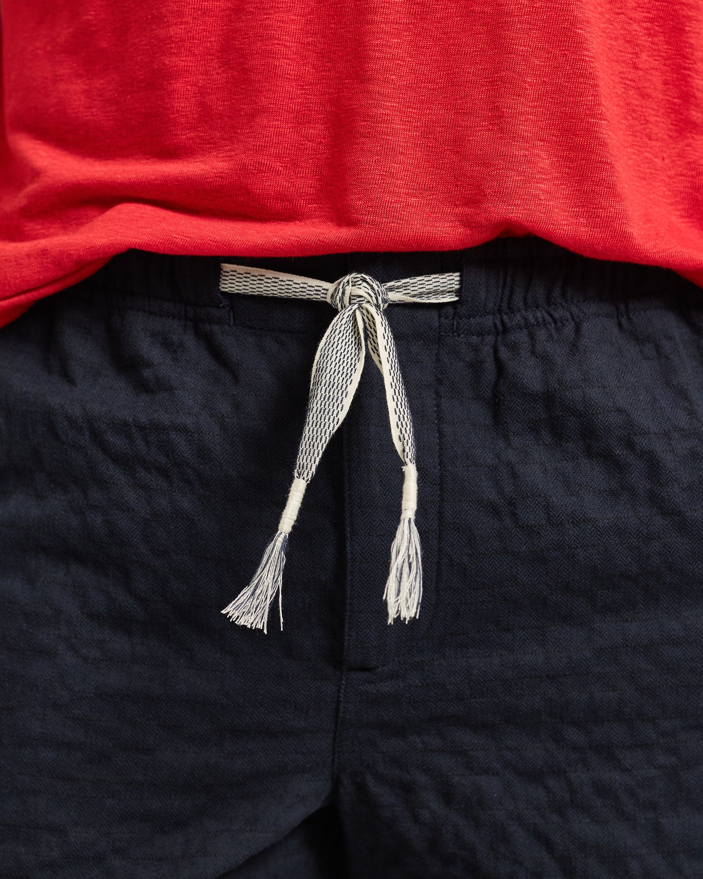 Navy shorts with a tied gray belt against a red background