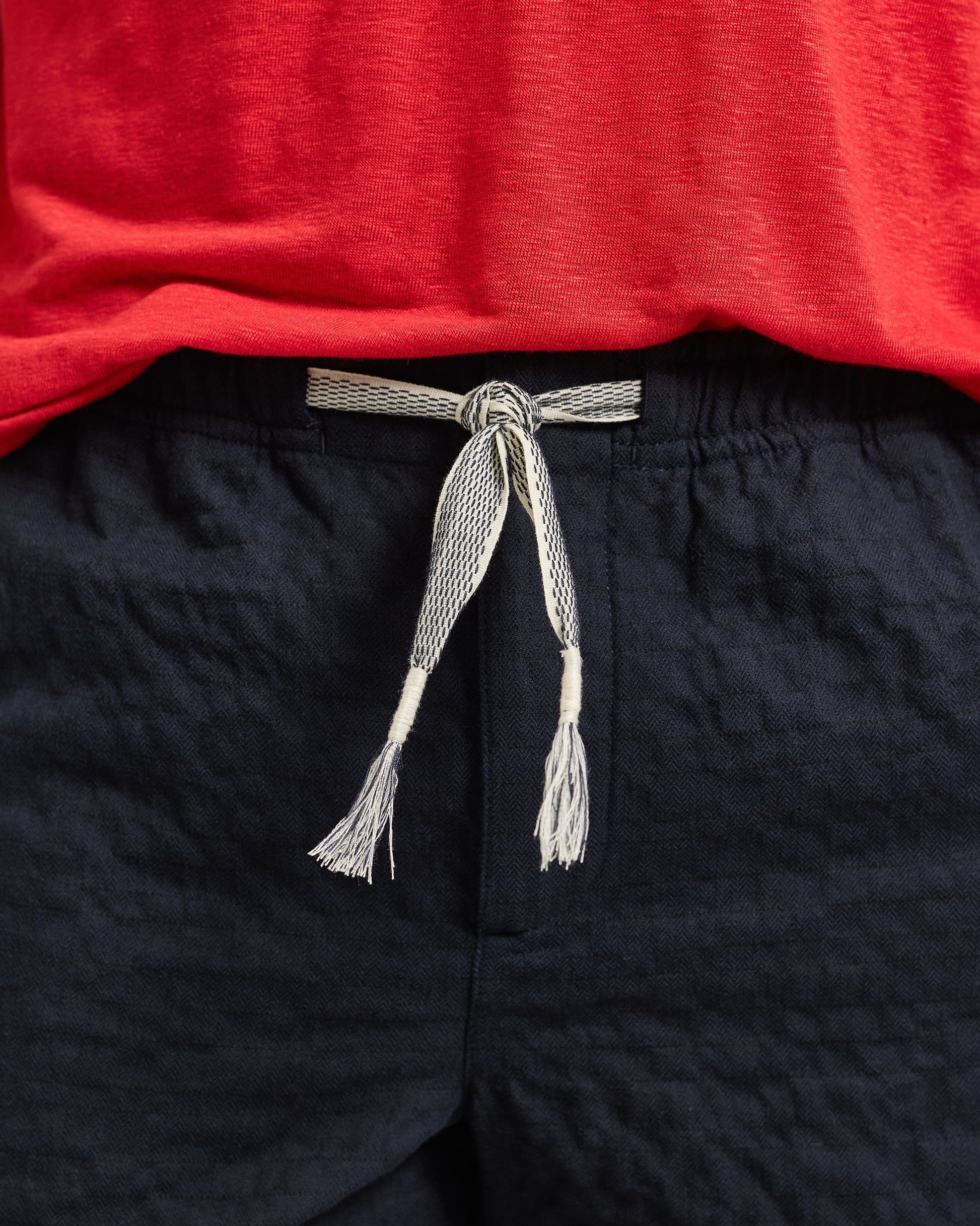 Navy shorts with a tied gray belt against a red background