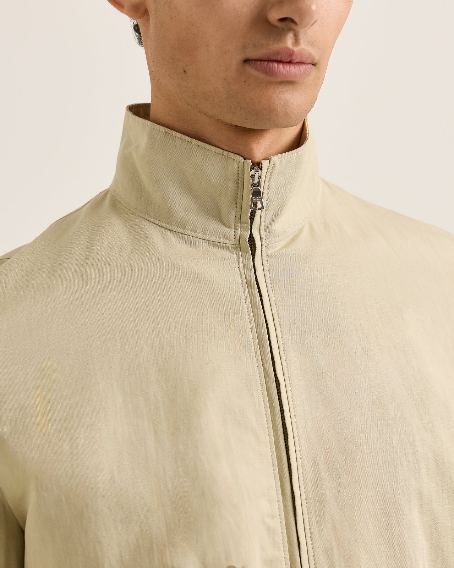 Close-up of a person wearing a beige jacket with a neutral background
