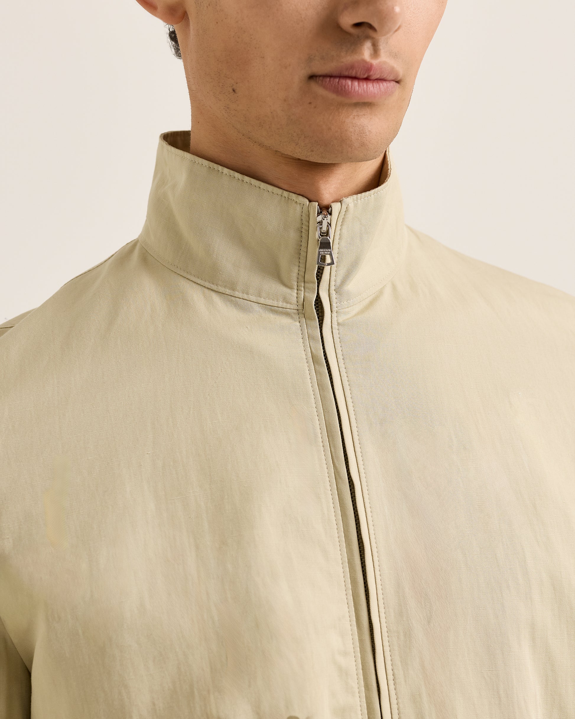 Close-up of a person wearing a beige jacket with a neutral background
