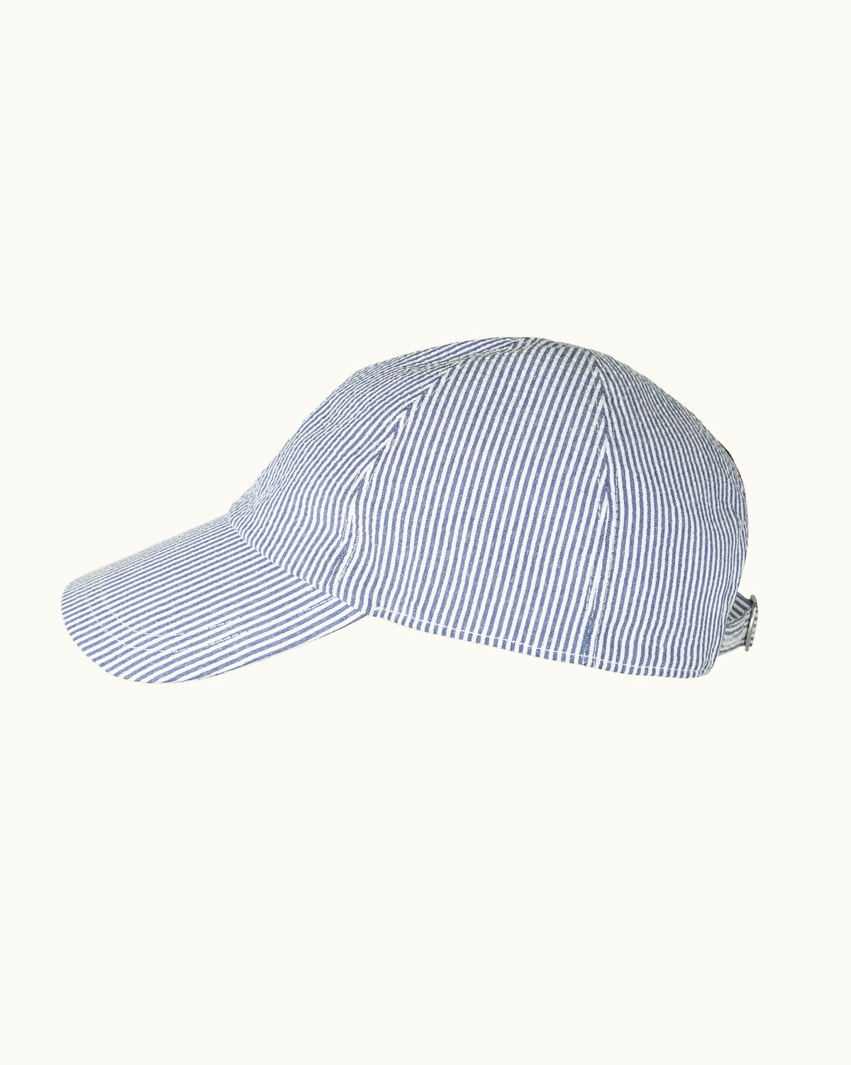 A blue and white vertically striped baseball cap shown from a side profile view against a solid off-white background.