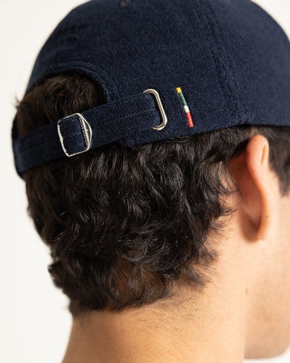Close-up back view of a person wearing a dark navy blue baseball cap with an adjustable strap and silver metal buckle.