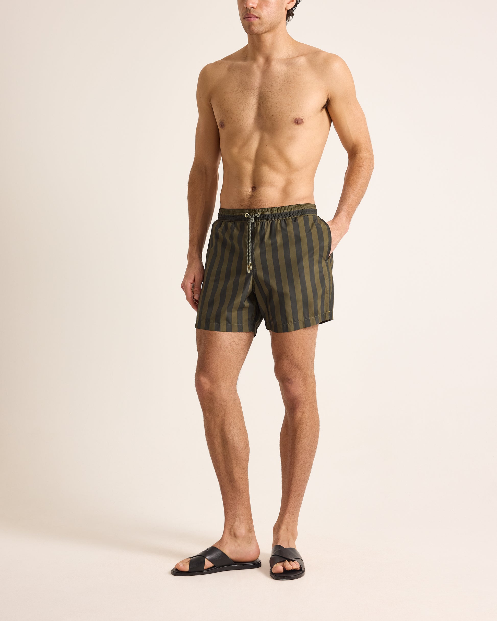 Man wearing striped swim shorts on a beige background