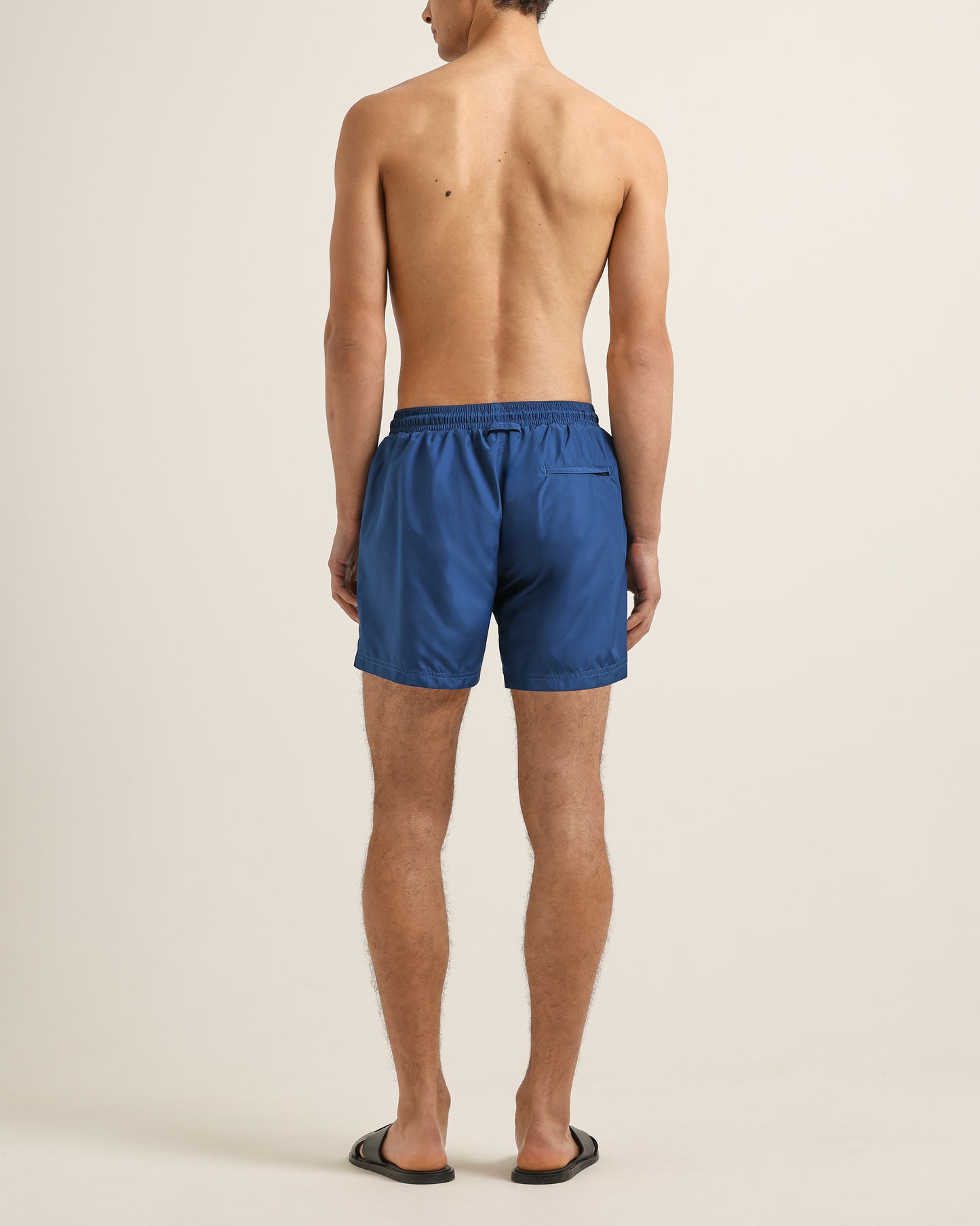 Man wearing blue swim shorts on a beige background
