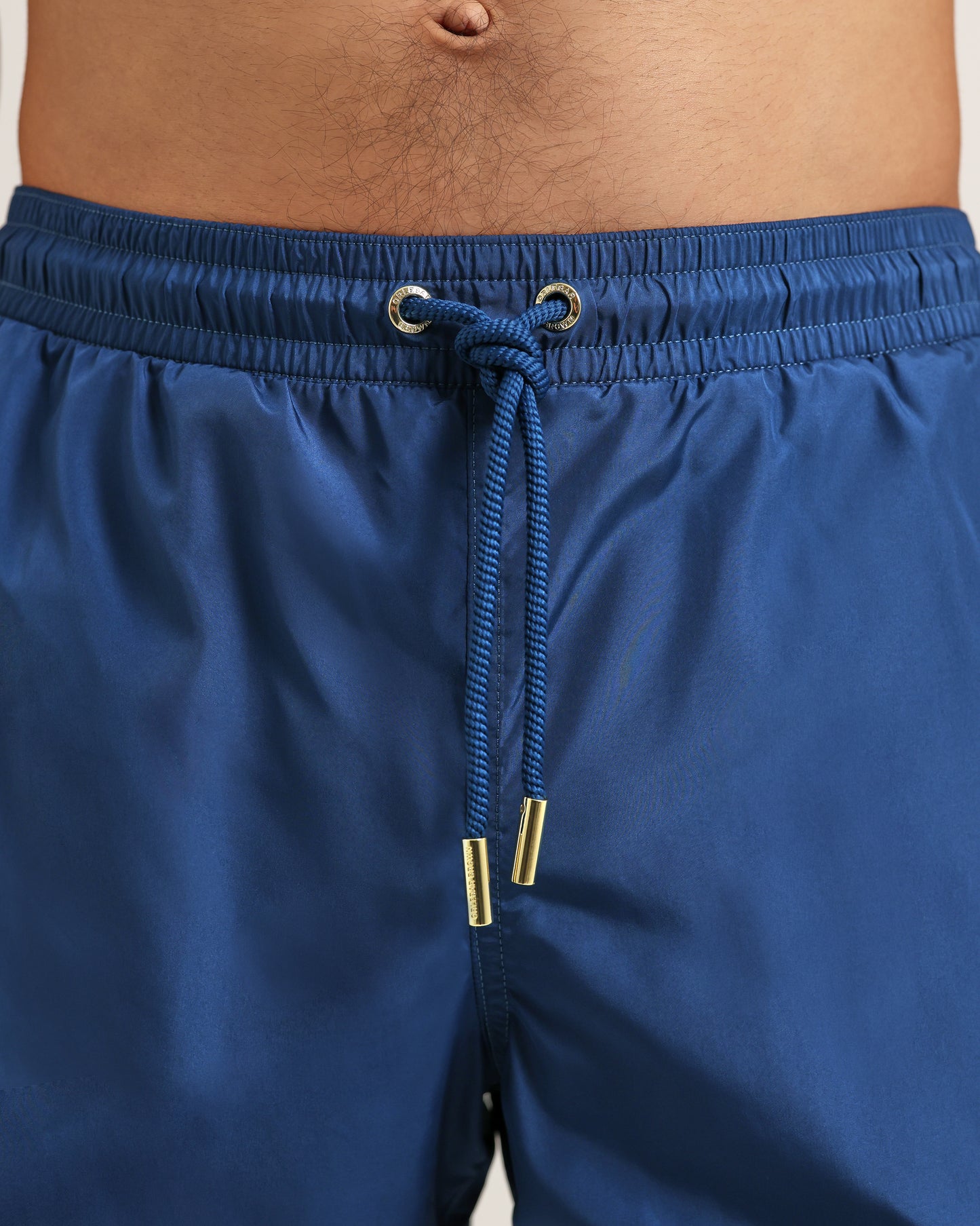 Blue swim shorts with a drawstring on a beige background