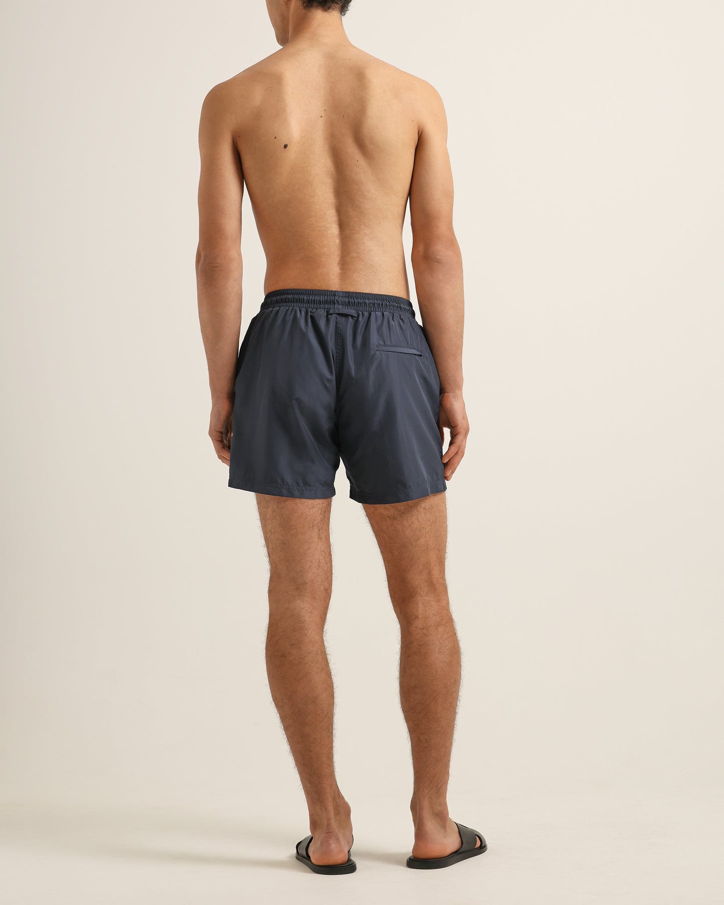 Man wearing grey swim shorts on a beige background