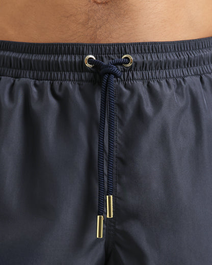 Grey blue swim shorts with drawstring and metal hardware on a person.