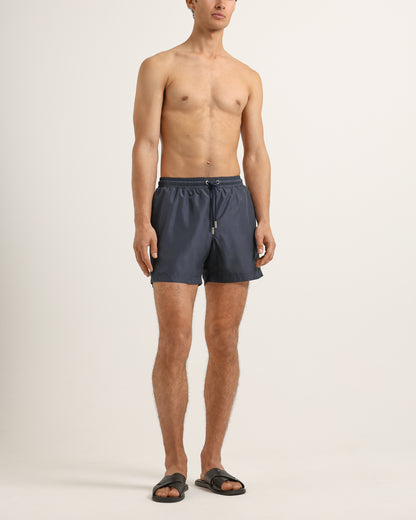 Man wearing dark gray swim shorts on a plain background