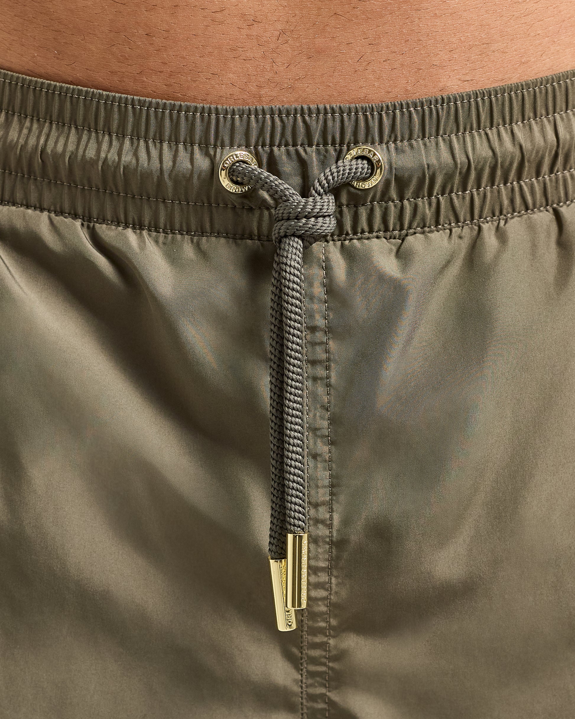 Close-up of olive green shorts with a drawstring and metal buckle.
