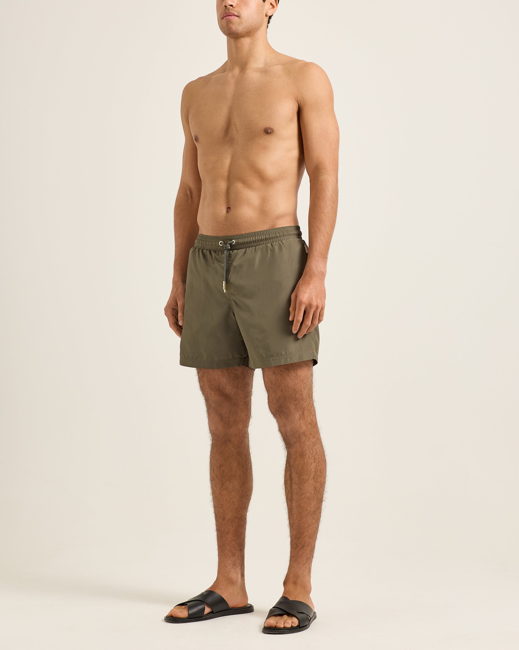 Man wearing olive green shorts on a beige background