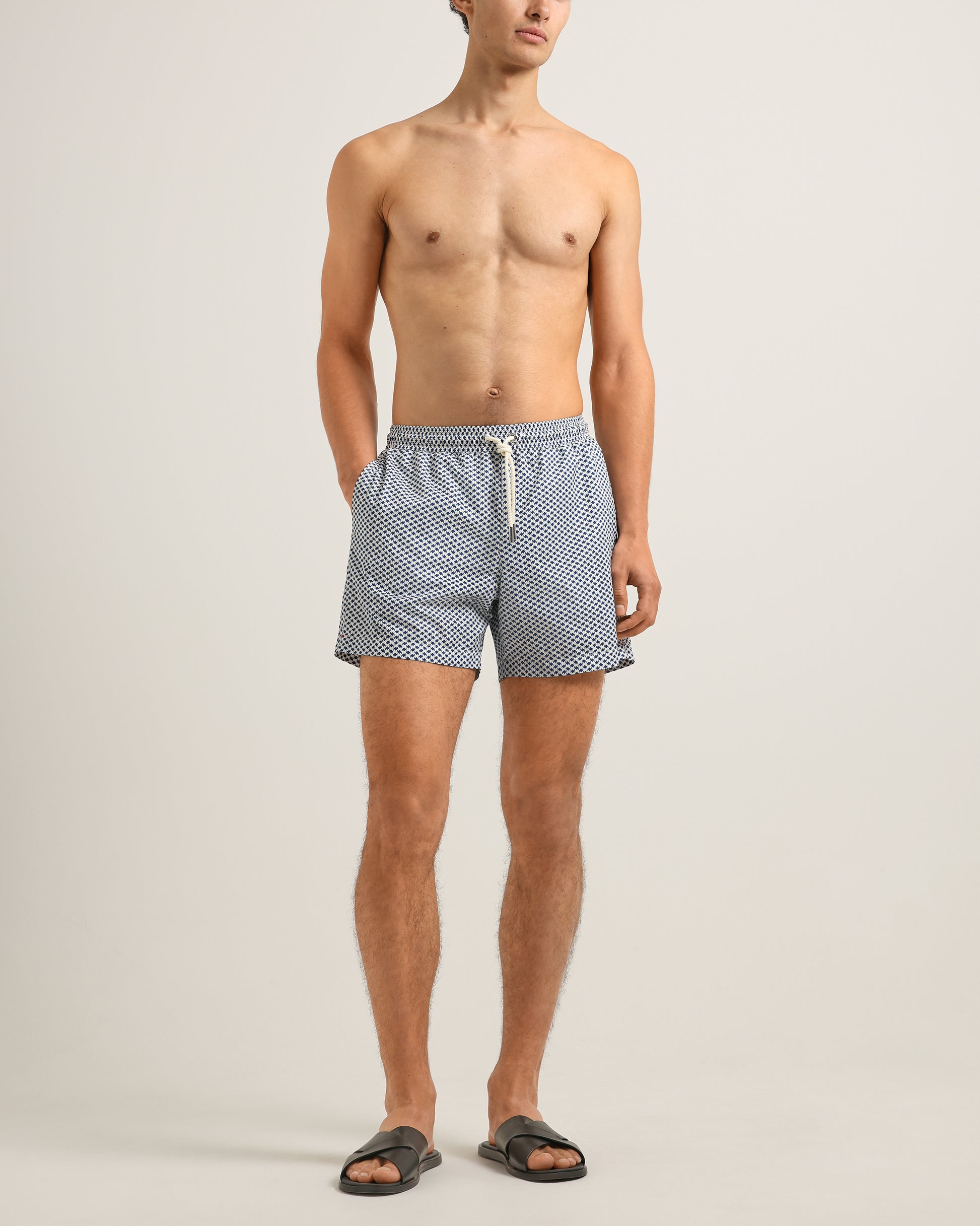 Man wearing blue checkered swim shorts on a plain background
