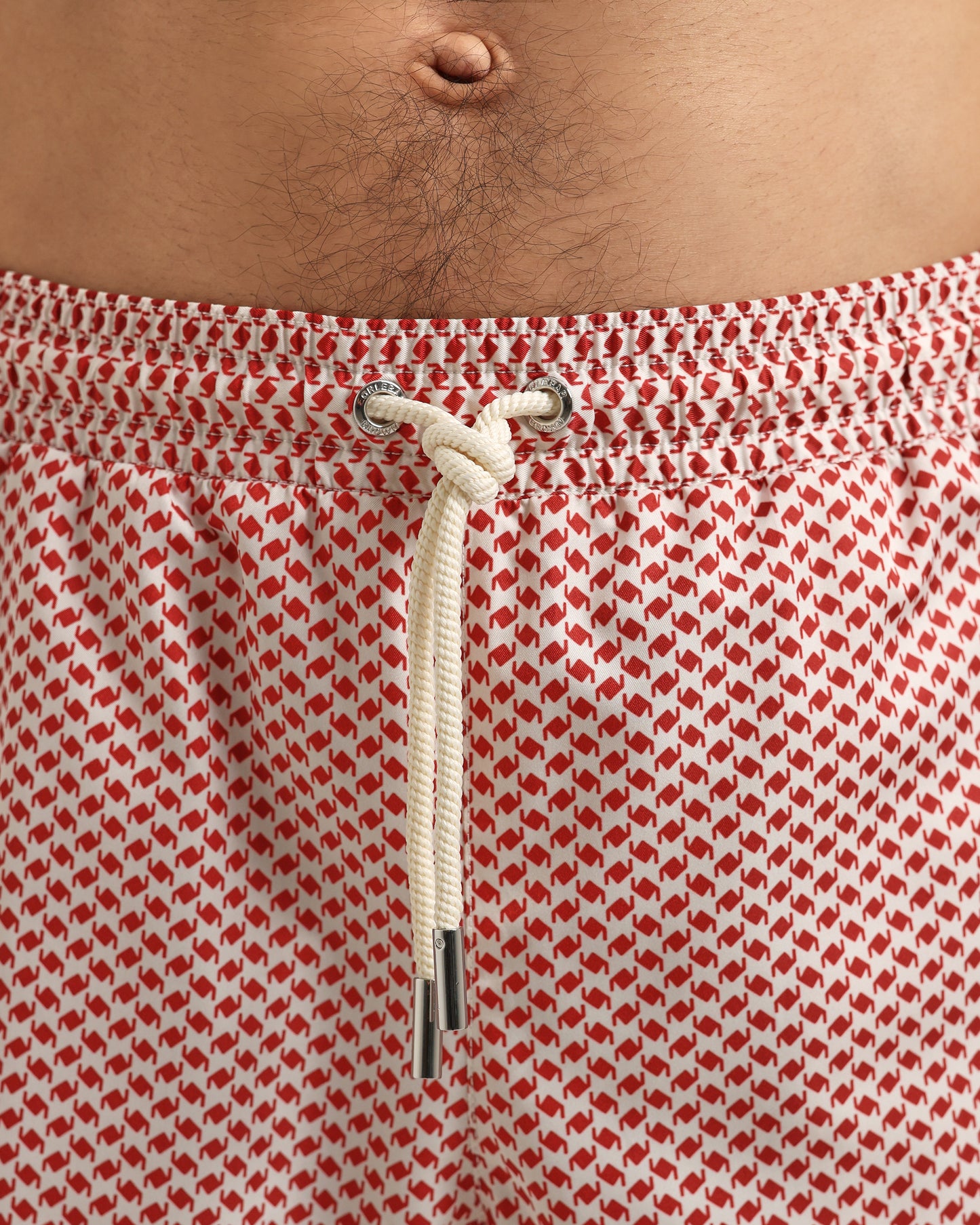 Red and white patterned swim shorts with a drawstring on a person.