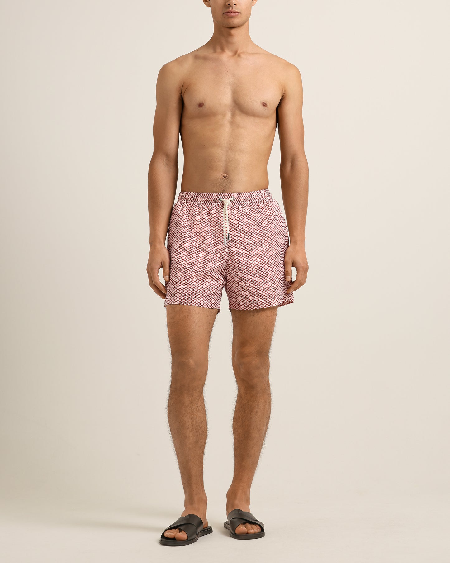Man wearing red checkered swim shorts on a beige background