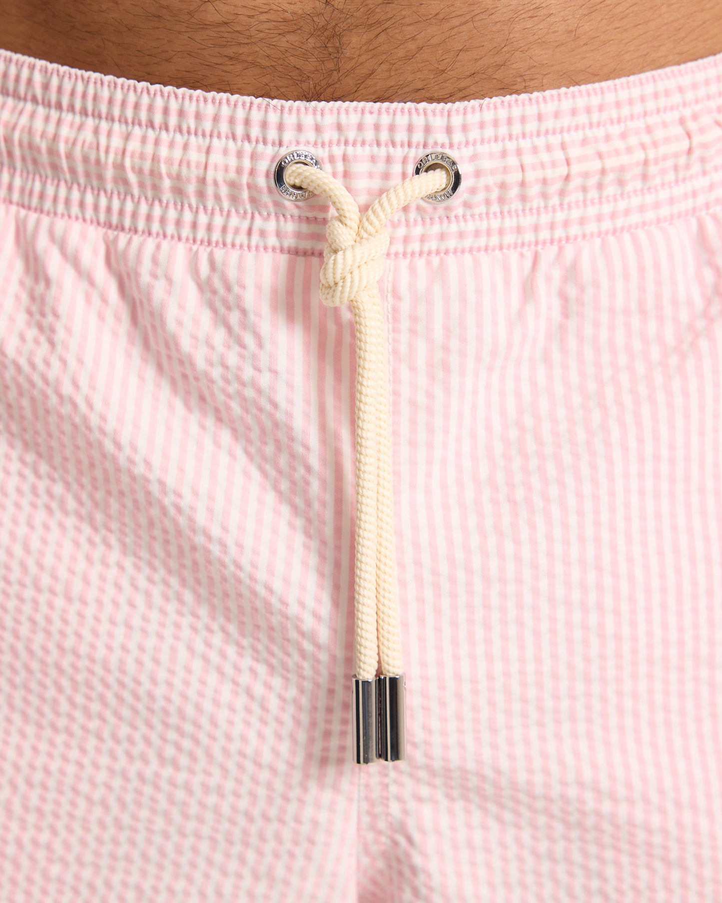 Close-up of pink seersucker shorts with a drawstring and metal grommets.